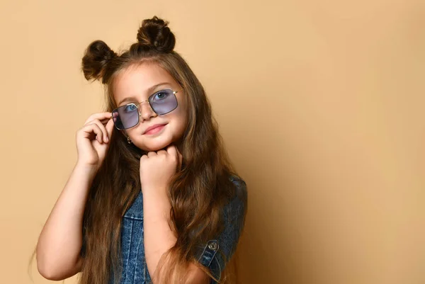 Schattig meisje in jeans sundress en zonnebril poseren op camera. — Stockfoto