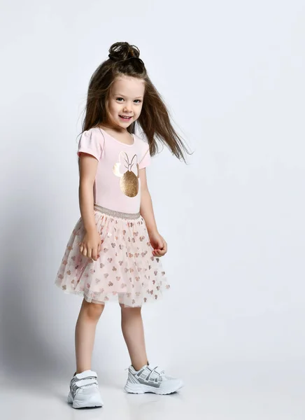 Μικρό χαμογελαστό χαριτωμένο κορίτσι με μακριά μαλλιά σε casual καλοκαιρινό φόρεμα και λευκά sneakers που στέκονται και κοιτάζουν την κάμερα — Φωτογραφία Αρχείου