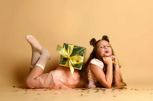 Mooi klein meisje liggend op de vloer met een geschenkdoos in de studio — Stockfoto