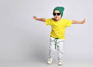 Yeşil şapkalı hippi çocuk geniş pantolonla dans ediyor.