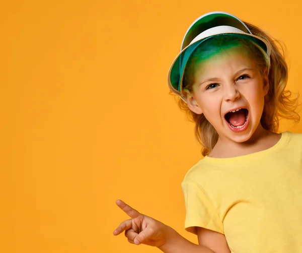 Klein lachend blond meisje in geel t-shirt die zich leuk voelt over een gele achtergrond. Gezond leven en schoon eten concept. — Stockfoto