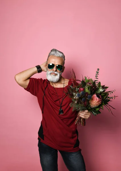 Hombre barbudo de mediana edad con corte de pelo moderno y suéter rojo de moda con un ramo de flores. Chico enamorado — Foto de Stock