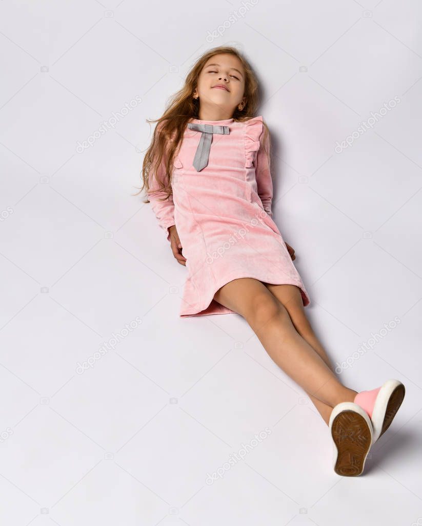 top view of a teenager girl in a casual pink dress and gym shoes. The style of youth and adolescents. On a light background.
