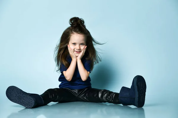 Klein lachend schattig meisje in t-shirt, lederen legging en donkerblauwe ugg laarzen poseren op de vloer — Stockfoto