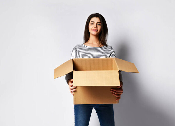 beautiful brunette woman standing on a light background with a moving cardboard box