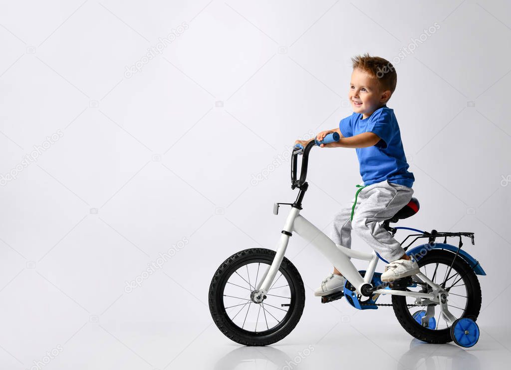 young boy happily riding on a bicycle on isolated background