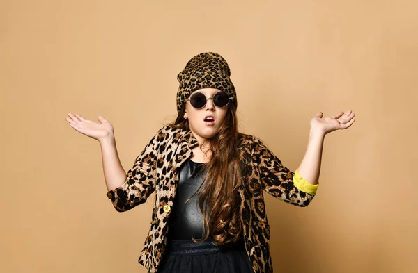 Joven modelo de niña de talla grande en ropa casual de color leopardo con estilo, falda negra y gafas de sol de pie y sintiéndose sorprendido — Foto de Stock