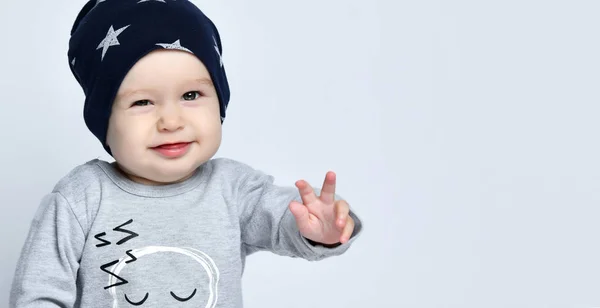 小男孩蹒跚学步，身穿灰色休闲装，头戴黑色帽子，脸上挂着微笑和手势 — 图库照片