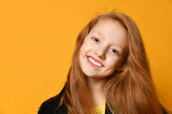 Niño adolescente pelirrojo con chaqueta negra. Ella sonríe y te mira, posando sobre fondo de estudio naranja. De cerca. — Foto de Stock