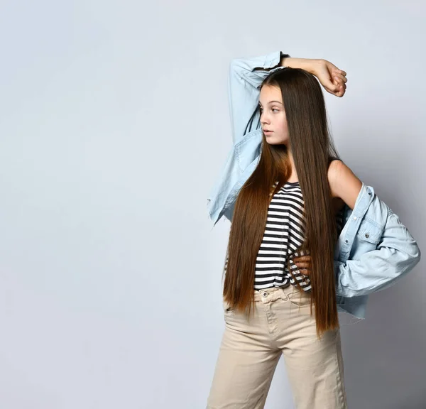Mujer adolescente con camiseta a rayas, chaqueta vaquera y pantalones. Te está mirando, posando aislada sobre fondo blanco del estudio. De cerca. — Foto de Stock