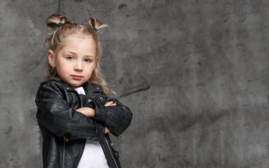 Şık rock tarzı siyah deri ceketli, kot pantolonlu ve beyaz spor ayakkabılı tatlı, güler yüzlü sarışın kız.