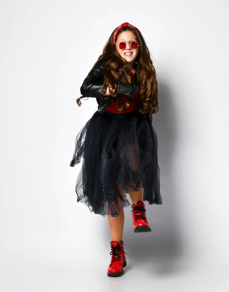 Joven modelo de chica positiva de talla grande en ropa de estilo rock brillante, botas rojas y gafas cuadradas bailando sobre fondo blanco — Foto de Stock