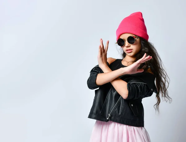 Дитина-підліток в чорній шкіряній куртці, рожевий капелюх і сонцезахисні окуляри. Показує зупинку або відсутність знаку з жестом, ізольовані на білому. крупним планом — стокове фото