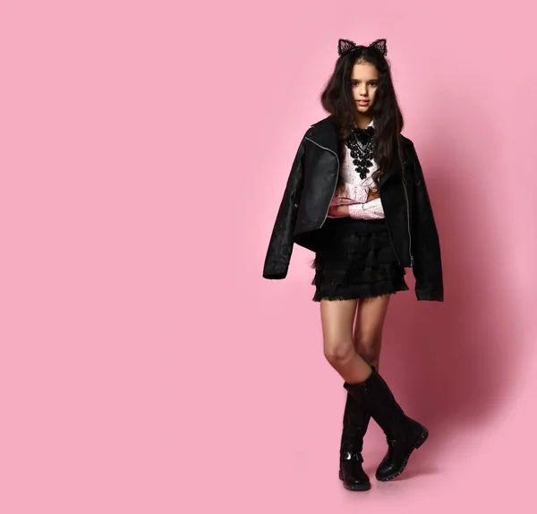 Teenager in white blouse, black jacket and boots, headband like cat ears. Posing on pink background. Copy space. Full length