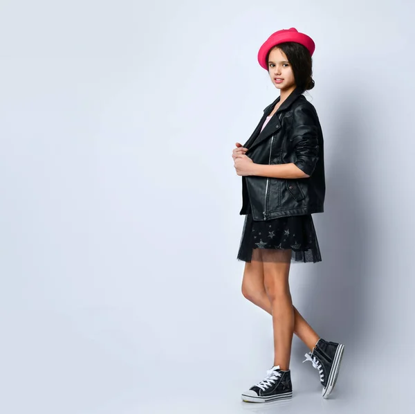 Siyah deri ceketli, etekli, tişörtlü, pembe şapkalı ve spor ayakkabılı genç kız. Beyazların üzerinde tek başına duruyor. Tam uzunluk — Stok fotoğraf