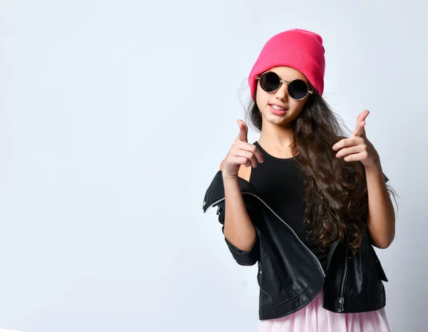 Adolescente donna in pelle nera giacca rosa cappello e occhiali da sole. Sta gesticolando mentre posa isolata sul bianco. Da vicino. — Foto Stock