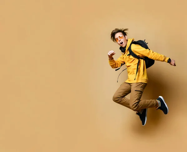 Retrato de un joven estudiante saltando en el estudio sobre un fondo beige —  Fotos de Stock