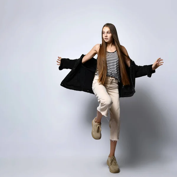 Adolescent in gestreept t-shirt, zwarte denim jas, broek en sneakers. Ze poseert geïsoleerd op een witte achtergrond. Sluiten. — Stockfoto