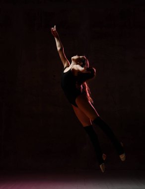 Siyah spor vücutlu genç bir jimnastikçi ve jimnastik pozisyonunda siyah arka planda zıplayan özel jimnastikçiler.