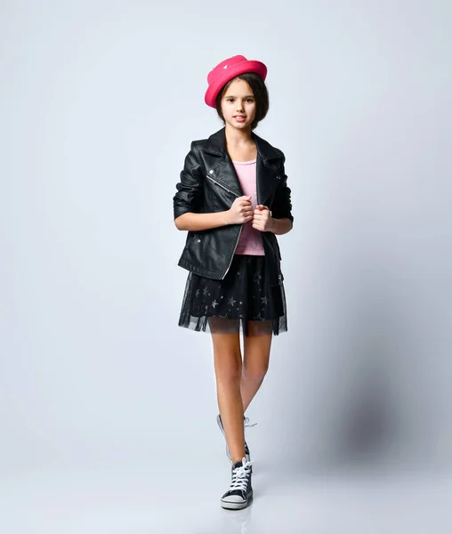 Teenage kid in black leather jacket, skirt, t-shirt, pink hat and sneakers. She smiling, standing isolated on white. Full length — Stockfoto