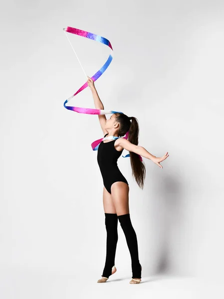 Giovane ginnasta ragazza in corpo nero sport e tomaie in piedi e fare esercizio con nastro ginnico su sfondo bianco — Foto Stock