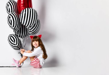 Stüdyonun arka planında bir sürü balonu olan tatlı bir kız.