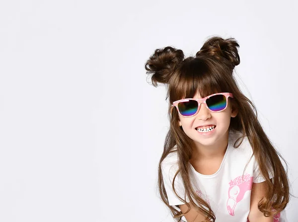 Una chica con una gran sonrisa en gafas de sol, en un estudio blanco . —  Fotos de Stock