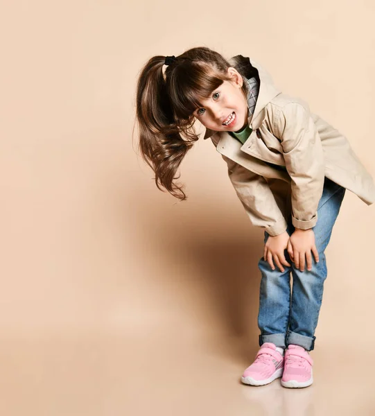 Schattig meisje poseren in verschillende poses, in jeans met riem, groen t-shirt en beige jas en roze sneakers — Stockfoto
