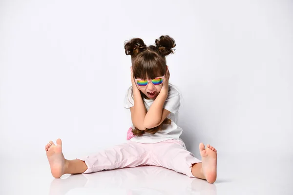 Девушка позирует сидя на полу, в Студии, в солнцезащитных очках и модной прическе, босиком — стоковое фото