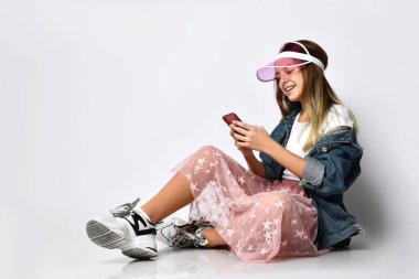 Gülümseyen kadın beyaz arka planda duran akıllı telefonu işaret ediyor..