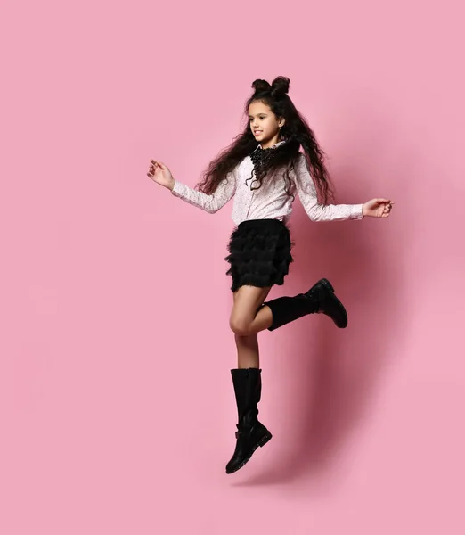 Adolescente hembra con pelo largo, en blusa blanca, falda negra y botas. Sonriendo y saltando sobre fondo rosa. Longitud completa — Foto de Stock