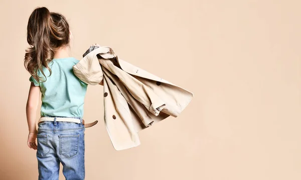 Den lilla brunetten står med ryggen vänd och bär en beige regnrock. — Stockfoto