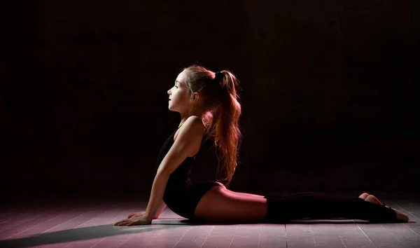 Adolescente flessibile, bella piccola ginnasta che fa esercizi ginnici per l'esercizio in classe di fitness, sfondo bianco scuro. — Foto Stock