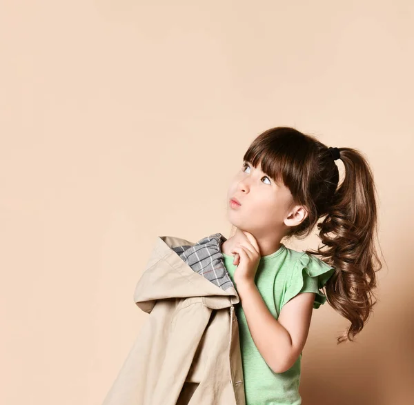 Surpresa bonito morena menina segurando um casaco bege em seu ombro . — Fotografia de Stock