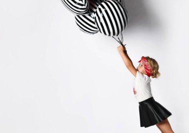 Kırmızı saç bandı takmış, beyaz tişörtlü küçük şirin bir kız elinde bir sürü balon tutuyor.