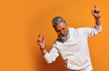 Modern, hippi iş adamının stüdyo fotoğrafı. Dans ediyormuş gibi yapıyor, turuncu arka planda izole edilmiş.