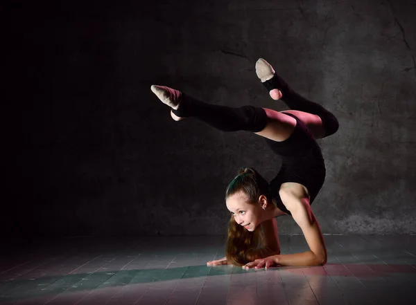 Teenage gymnast in black leotard, knee socks and ballet shoes, performing exercises standing on her hands, upside down. Close-up — Stock Photo, Image