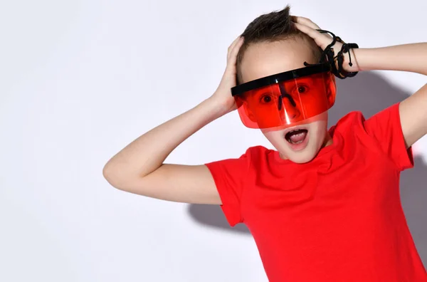 Tonårskille i överdimensionerade solglasögon, röd t-shirt, svarta armband. Han ser chockad, kramande huvud, poserar isolerad på vitt — Stockfoto