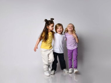 Renkli günlük kıyafetler giymiş küçük oğlanlar ve kızlar. Birbirlerine gülümsüyor ve sarılıyorlar, beyazların üzerinde yalnız poz veriyorlar.