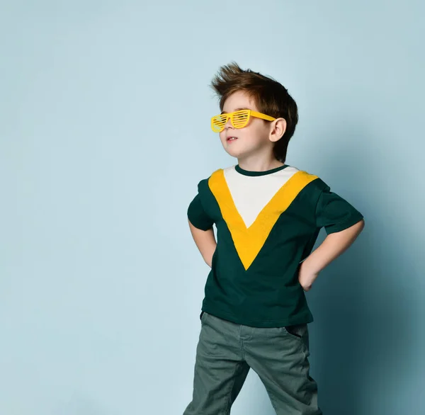 Mały, modny mężczyzna w śmiesznych okularach w paski, pozujący na niebieskim tle studia — Zdjęcie stockowe
