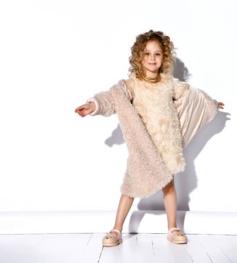 Altın kolyeli, tüylü pembe elbiseli, kürklü, ayakkabılı küçük sarışın manken. Ellerini aç, gülümse, bembeyaz poz ver.