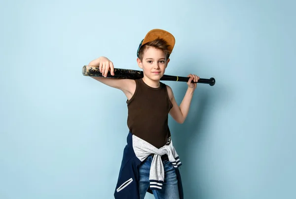 Niegrzeczny dzieciak z uśmiechem na twarzy, trzymający kij bejsbolowy za głową. Trzy czwarte długości portret izolowany na niebieskim tle — Zdjęcie stockowe