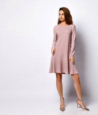 Kısa mercan pembesi elbisesi ve yüksek topuklu ayakkabıları olan, beyaz tenli, sevimli gülümseyen genç bayan. Zarafet, şık kıyafetler, kadınlar için moda..