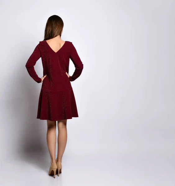 Вид спереду красива молода жінка в блискучій червоній короткій сукні, що позує хрестоподібними ногами на високих підборах. Портрет повної довжини ізольований на білому. Копіювати простір — стокове фото
