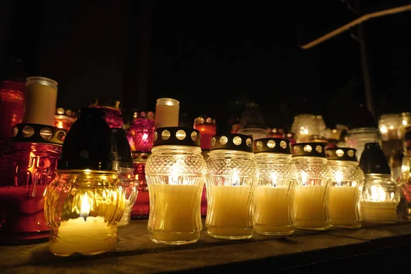 burning colorful candles in jars in the cemetery on the occasion souls of the deceased at night Poland Religion tradition. holiday as the remembrance day. graveyard on the day of the dead