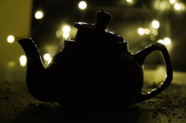 Karanlık bir arka planda çaydanlığın gölgesi ve ampuller. Karanlık arka plan. Klasik siyah seramik çaydanlık.