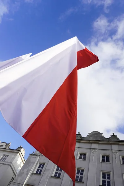 Bandiere rosse e bianche polacche nella città vecchia di fronte all'edificio in una giornata di sole. 1 maggio, 11 novembre, bandiera, indipendenza o festa del lavoro. Festività in Polonia. decorazione della città con bandiere . — Foto Stock