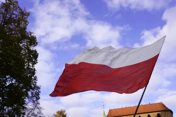 Drapeaux rouges et blancs polonais dans la vieille ville en face du bâtiment par un jour ensoleillé.1er mai, 11 novembre, drapeau, indépendance ou fête du travail.Jours fériés en Pologne.drapeau sur fond de ciel bleu avec des nuages — Photo