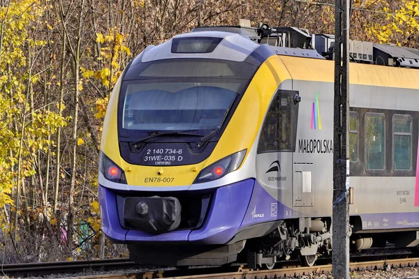 Polônia, Cracóvia: 13.11.2019 - bonde ecológico na cidade, rota turística no Parque, caminhada pela cidade de outono, carros elétricos modernos.velha estação abandonada e estradas de acesso, trilhos envoltos planta à direita . — Fotografia de Stock