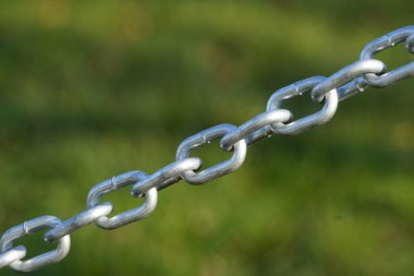 Çelik, metal ya da gümüş renginde sade zincir bir çayırın arka planında ya da yeşil otlu çimlerde.